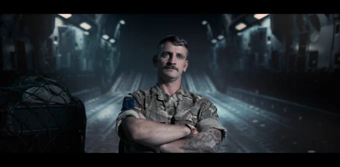 Man in combats sits in the back of a military aircraft to be interviewed - the image is a still taken from the trailer of a film.