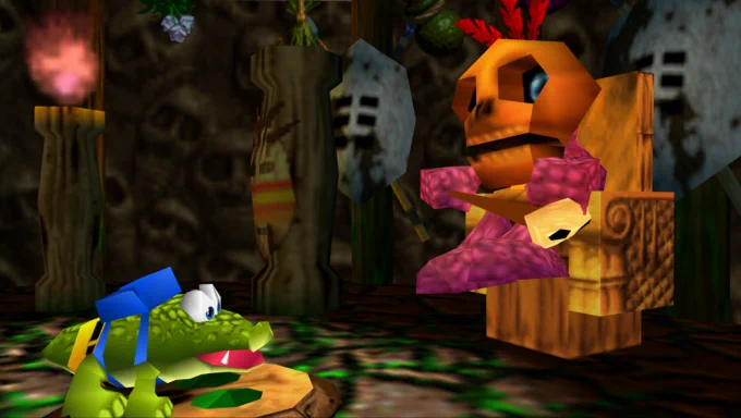 A skull-faced shaman sits on a chair holding a skull-topped stick. In front of him stands a small crocodile with yellow shorts and a blue backpack.