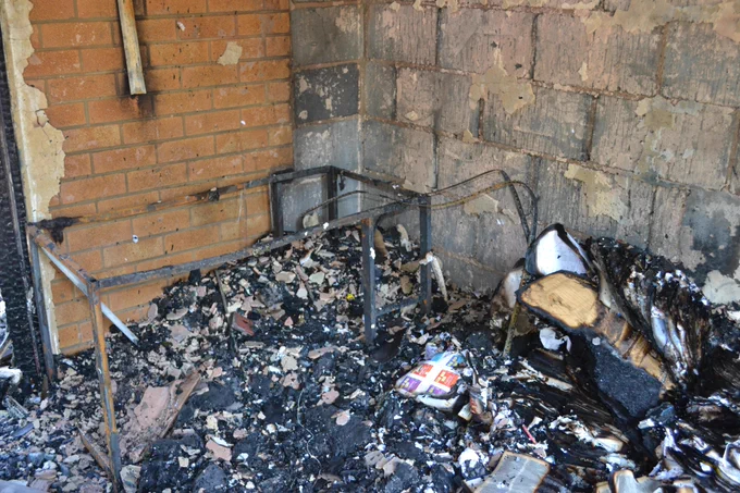 The frame of the dining table can be seen in the corner of a fire damaged room.