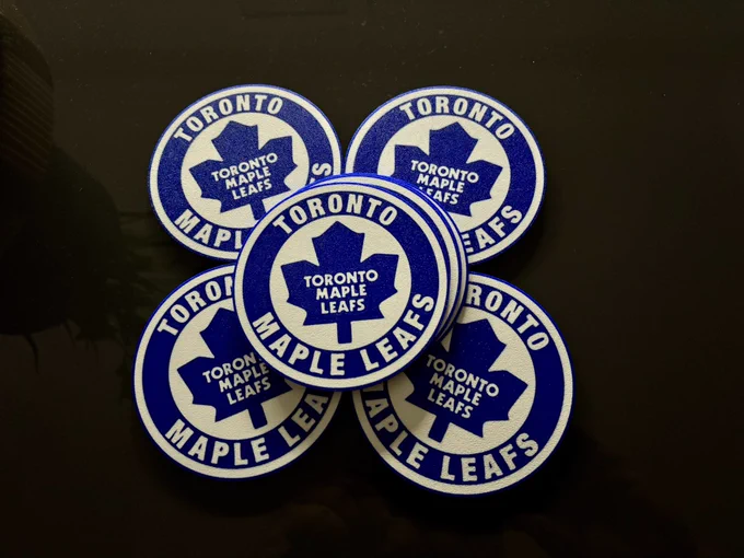 A set of blue & white maple leafs coasters sit on a dark coffee table