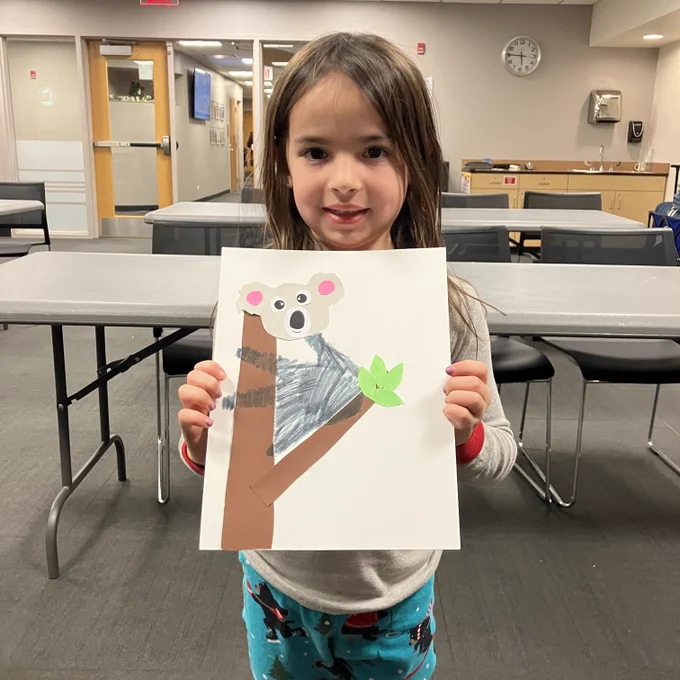 A young patrons holds up her koala artwork.