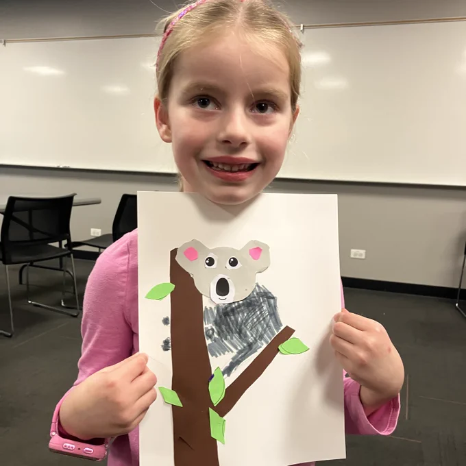A young patrons holds up her koala artwork.
