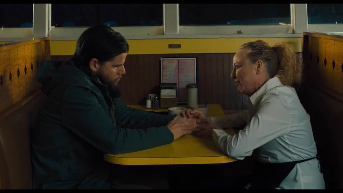 A veteran shares a quiet, emotional moment with a diner server in Sheepdog, a scene that captures the fragile space between isolation and human connection during post-deployment life. (Credit: Team House)