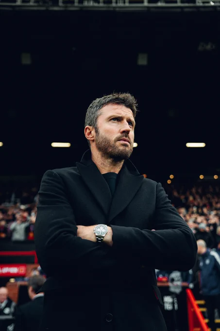 Michael Carrick stands with his arms folded on the touchline at Old Trafford.