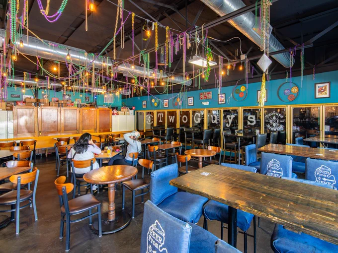 Interior of Two Guys Brewery with colorful decor, string lights, and several patrons dining at tables.