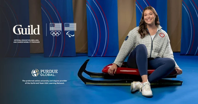 Smiling athlete sitting on a luge sled, in a studio setting with striped red, white, blue, and gold banners. The logos for Guild, Team USA, and Purdue Global are next to her.