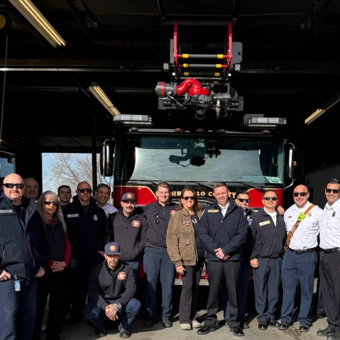 Group of firefighters and officials standing in front of a Bernalillo County Fire Rescue truck.
