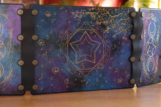 A DM screen with galaxy leather and gold summoning circles and cherry blossom branches