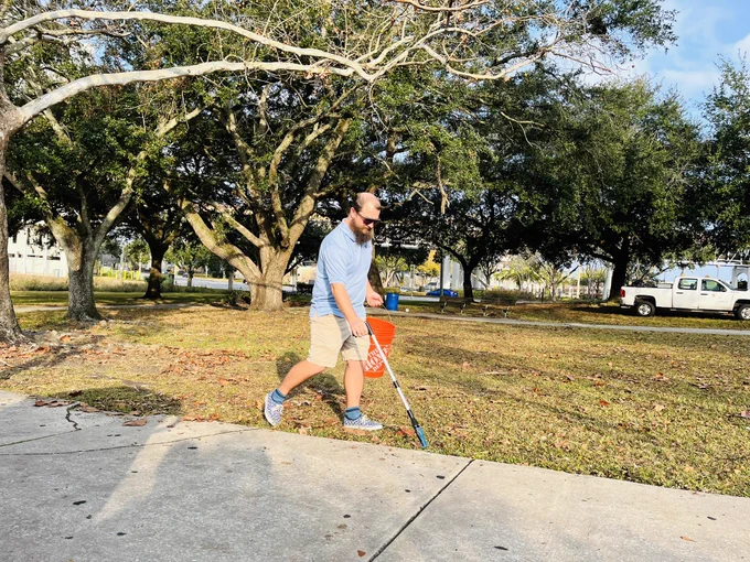 A person picking up litter with a grabber