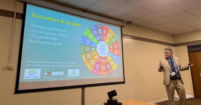 Prof Mark Sutton presents a slide titled "Everywhere & Invisible," highlighting nitrogen pollution's relevance to UN sustainable goals. A colourful wheel illustrates this connection.