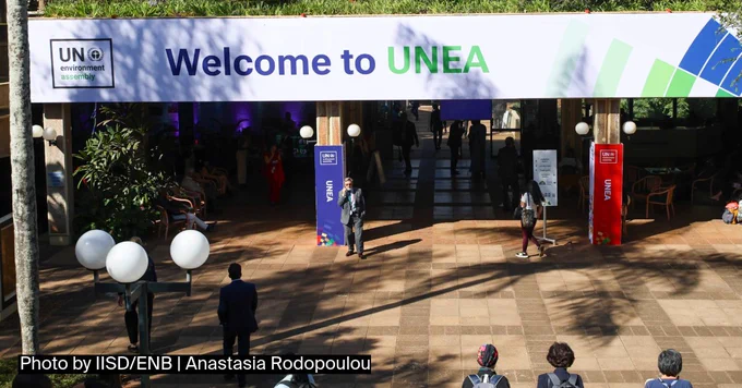 Banner reading "Welcome to UNEA" at the entrance of a conference venue, with participants walking and gathering below.
