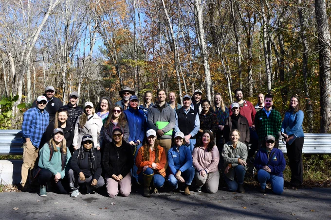 A large group of people posing outside in the autumn.