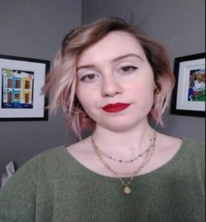 Photo of a woman in a green shirt with a gold necklace and red lipstick and blonde/pinkish hair
