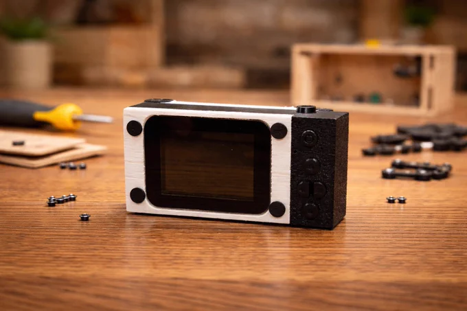 Wokit #2, the camera, sits on a warm wooden floor with pieces scattered nearby, giving a cozy and inviting vibe. Imagining a parent and child playing together completes the scene of creativity and shared memories.
