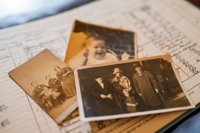 Old black and white photographs sitting on an open register book.