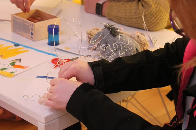 Hands shown making a wire sculpture.