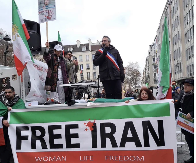 Ma prise de parole sur une estrade aux couleurs de l’Iran et au slogan Woman Life Freedom
