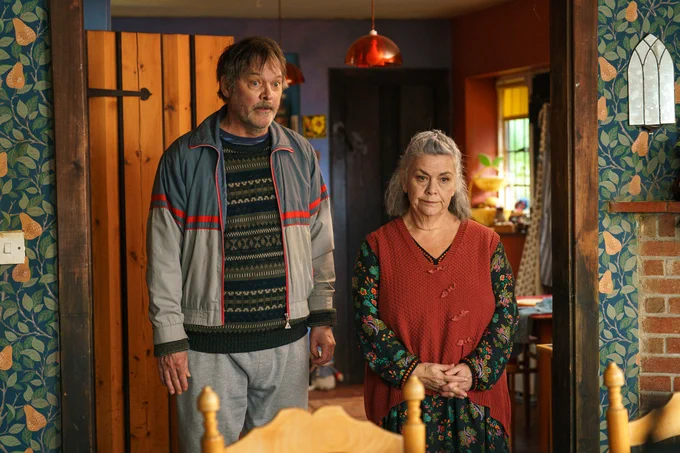 Mark Heap and Dawn French's characters at home, dressed casually and looking guiltily at someone