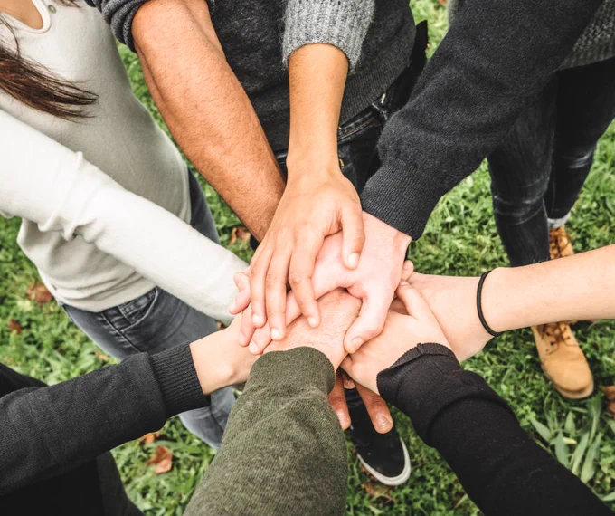 A close up photo of a group of hands on top of one another in a circle.