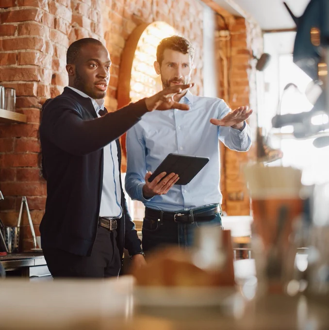 Two business men in a café surveying the area. 