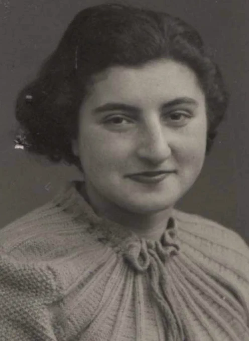 Black and white portrait of a woman, featuring a close-up of a smiling individual in a knitted top.
