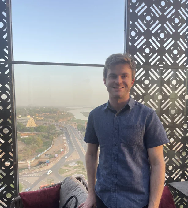 Grady McGinnis in front of a window on an assignment for USAID.