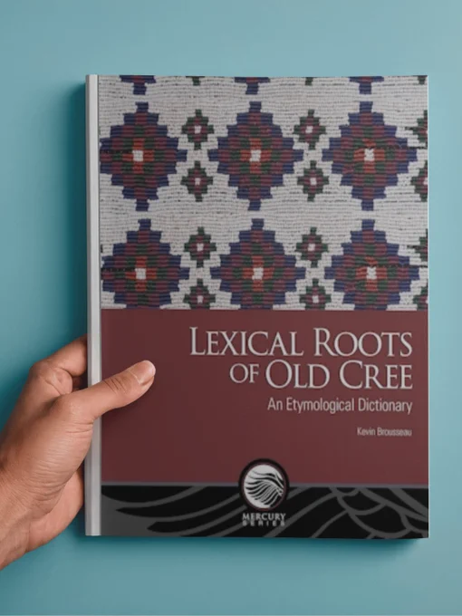 Une personne tenant un livre intitulé "Lexical Roots of Old Cree" par Kevin Brousseau, publié par la Collection Mercure Mercury. La couverture présente un motif décoratif.