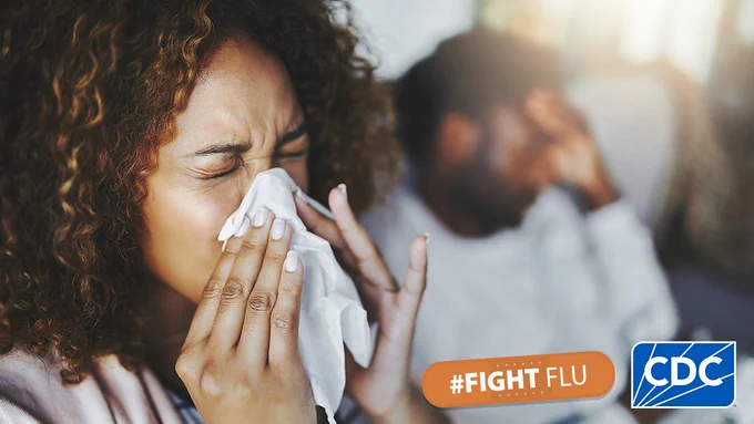 A woman holds a tissue on her nose as she sneezes. In the bottom-right hand corner is the #FightFlu logo next to the CDC logo. 