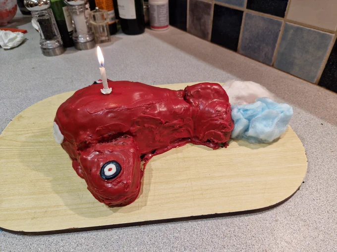 Aeroplane-shaped birthday cake, trailing blue and white "smoke".
