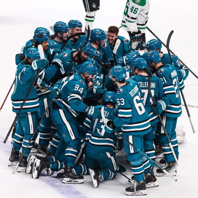 Sharks players on ice in Sharks uniforms celebrating their overtime win.