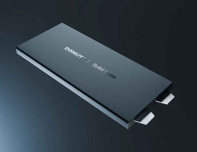 Slim, dark gray rectangular solid-state battery labeled “DONUT LABS | Solid State,” shown at an angle with two metal connector tabs protruding from one end against a dark gradient background.