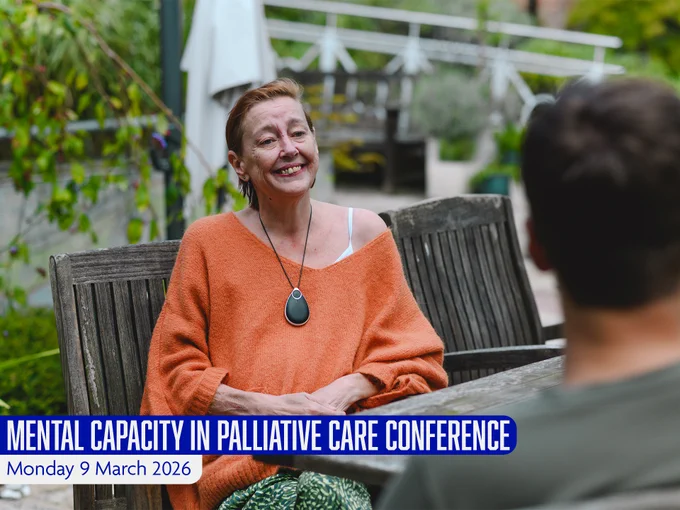 Person sat smiling in a hospice garden, speaking to a member of staff in casual wear. The text overlay reads: "Mental Capacity in Palliative Care Conference, Monday 9 March 2026".