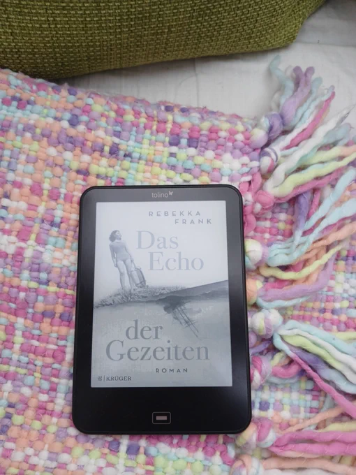 eBook auf bunt gemusterter Wolldecke und moosgrünen Kissen. 
Rebekka Frank, Das Echo der Gezeiten
