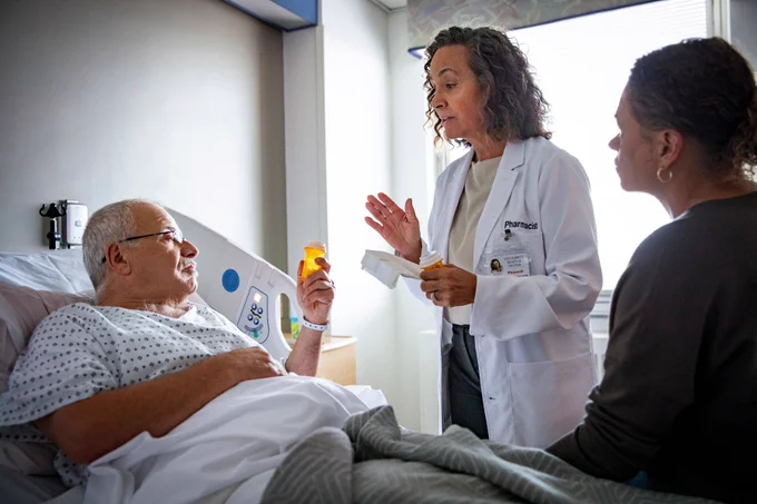 Photo of pharmacist consulting patient in hospital setting.