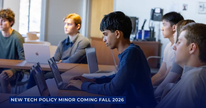 Students sitting in a classroom at tables that have laptops on them. Text beneath the photo says: New tech policy minor coming fall 2026. 