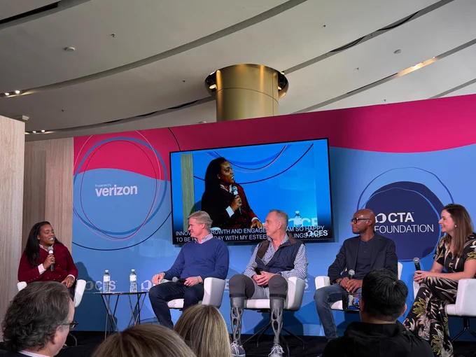 Photo of 4 people talking on a panel at CES. 
