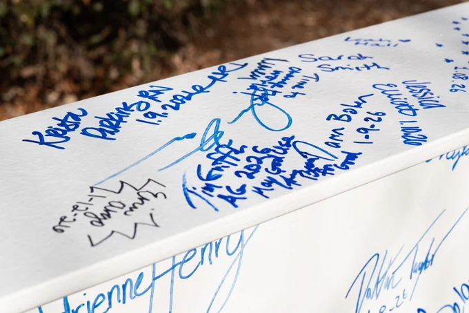 Close-up of a white steel beam covered with various signatures.