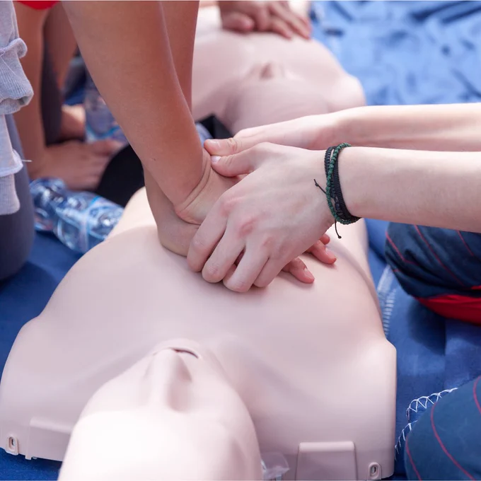 person practicing chest compressions on a CPR manikin