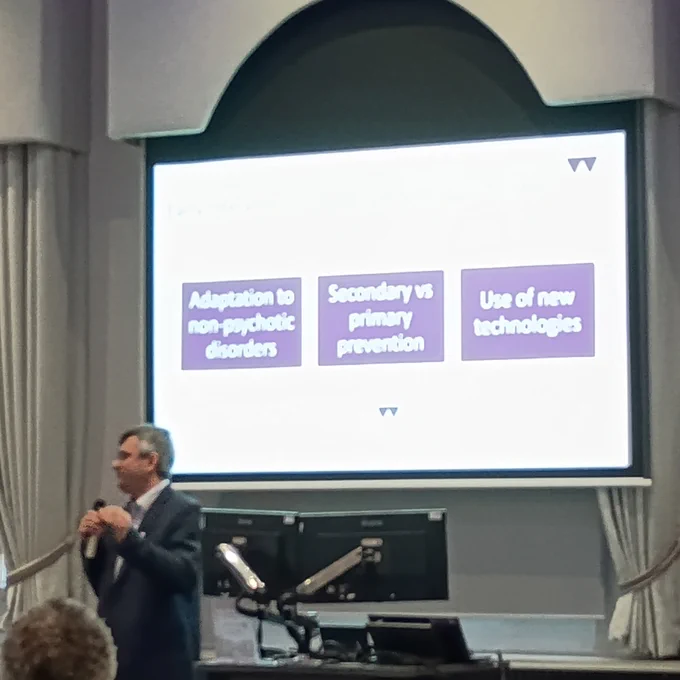 Prof Domenico Giacco talking in front of a slide showing 3 boxes - adaptation to non-psychotic disorders; secondary vs primary prevention; use of new technologies.