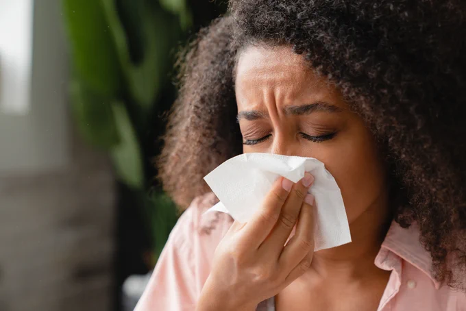 Woman blowing nose with a tissue.