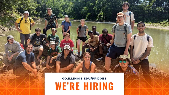 A group of individuals on a summer day standing in front of a river, smiling, and facing the camera. At the bottom center, there's a white box with text that says, "go.illinois.edu/prijobs" and "we're hiring."