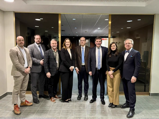 Minister Dominic LeBlanc poses for a group photo with representatives from the dairy and aluminum industries in Montreal.