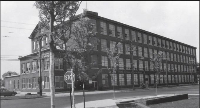 Black-and-white photograph of an early SUNY College of Technology building, showing a multi-story brick structure with rows of windows.