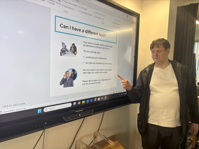 David standing by a monitor with photos and words on the screen