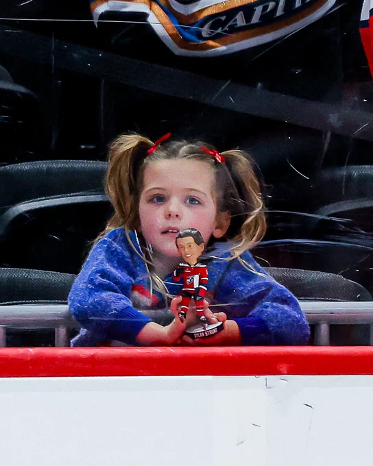 Dylan Strome's daughter holds his bobblehead on the glass during warmups. 
