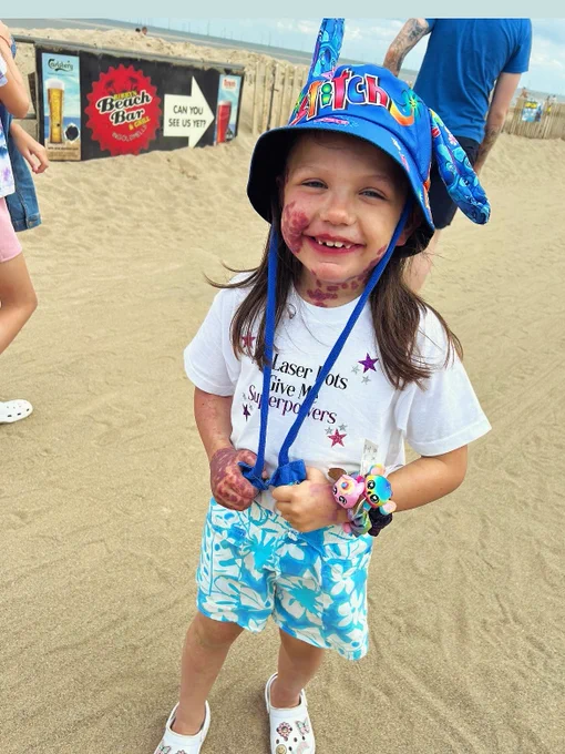Lacey this summer, at the beach, in a sun hat and t-shirt and board shorts.