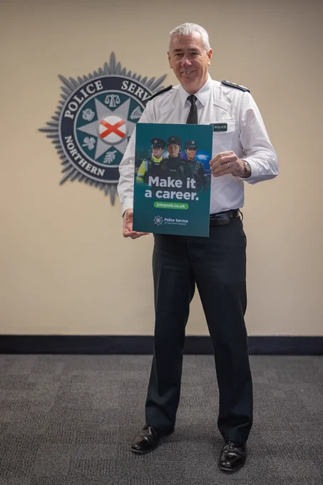 Chief Constable Jon Boutcher holding a PSNI Student Officer recruitment poster.