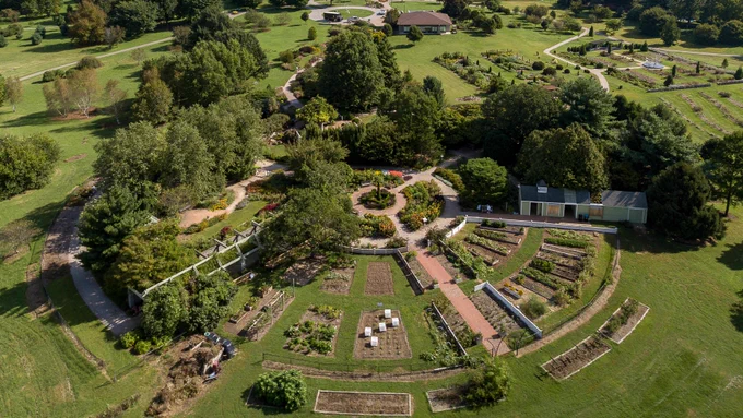 An aerial view of the UK arboretum, showing trees, lawn, and planted areas. 