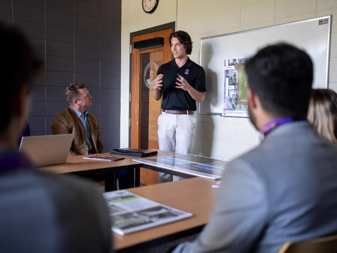 Student presenting in front of class and business professionals