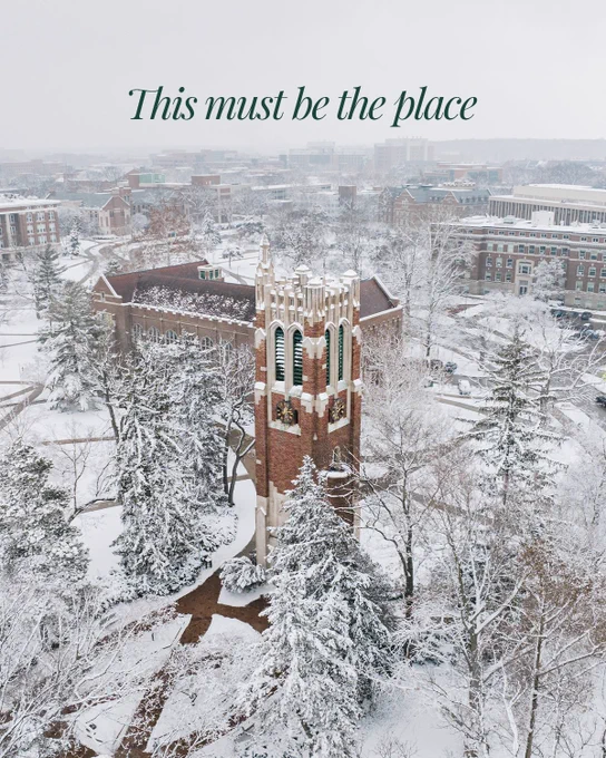 A snowy day view of Beaumont Tower among snow covered buildings and trees with text that reads, "This must be the place".